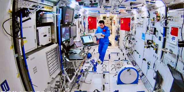 This photo taken and released on August 20, 2021, by China Manned Space Engineering Office via CNS shows Chinese astronaut Tang Hongbo coordinating inside the Tianhe core module as his colleague Nie Haisheng conducts a spacewalk.