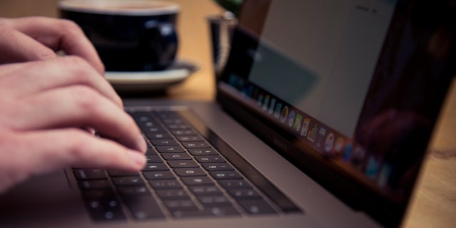 Detail of someone typing on the keyboard of an Apple MacBook Pro laptop computer in a cafe, taken on November 18, 2016. 