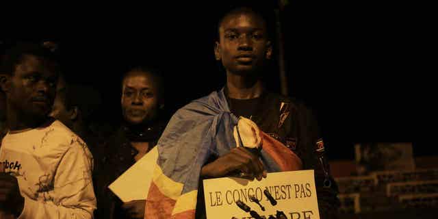 A young man is wrapped in the Democratic republic of Congo flag in Beni on Dec. 7, 2022, during a prayer vigil in remembrance of the victims of the ongoing unrest in the country. At least 131 civilians were killed by M23 rebels in eastern Democratic Republic of Congo, according to a United Nations investigation.