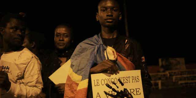 A young man is wrapped in the Democratic republic of Congo flag in Beni on Dec. 7, 2022, during a prayer vigil in remembrance of the victims of the ongoing unrest in the country. At least 131 civilians were killed by M23 rebels in eastern Democratic Republic of Congo, according to a United Nations investigation.