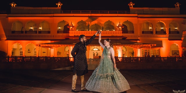 The couple raises their hands together. The bride said she is "so happy that all my friends and family and all of his friends and family blended so well together."