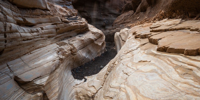 An asphalt trail leads through the smooth white polished marble walls in Mosaic Canyon, Death Valley National Park, California.