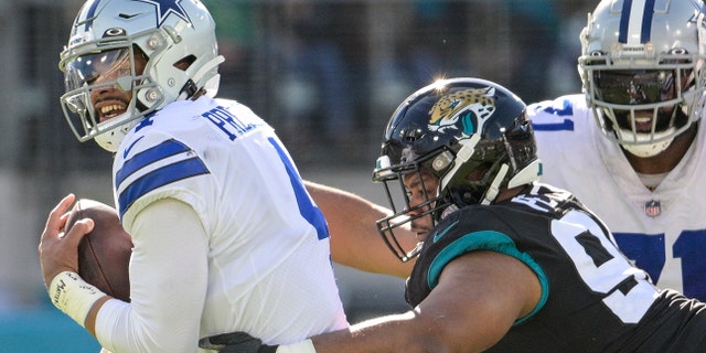 Dallas Cowboys quarterback Dak Prescott, left, is sacked by Jacksonville Jaguars defensive tackle Corey Peters (98) during the first half, Sunday, Dec. 18, 2022, in Jacksonville, Florida.