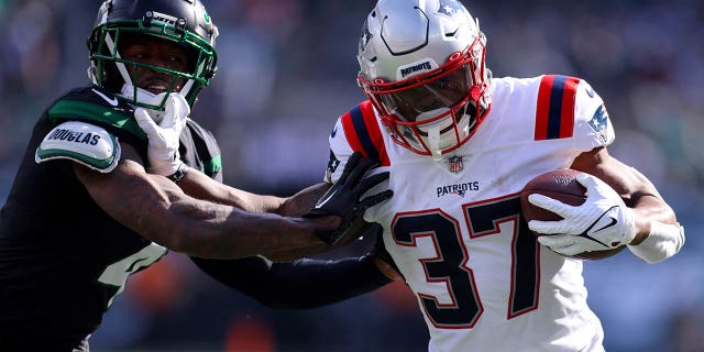 Damien Harris #37 of the New England Patriots runs with the ball as DJ Reed #4 of the New York Jets defends during the first half at MetLife Stadium on October 30, 2022 in East Rutherford, New Jersey.