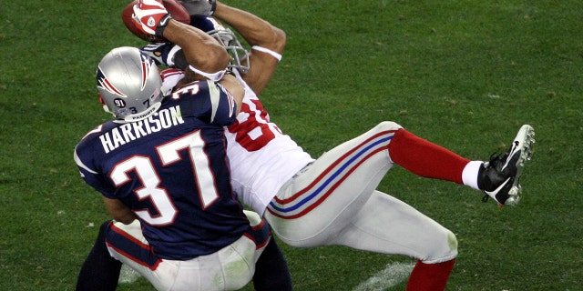 New York Giants' wide receiver David Tyree pins the ball to his helmet as he catches a 32-yard pass late in the fourth quarter of Super Bowl XLII against the New England Patriots at the University of Phoenix Stadium.