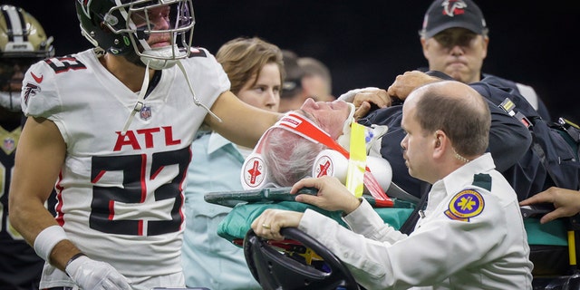 Atlanta Falcons defensive coordinator Dean Pees, on a backboard, is fist-bumped by Erik Harris.