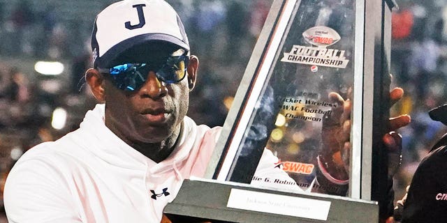 Jackson State head coach Deion Sanders hoists the winner's trophy following the Southwestern Athletic Conference championship game against Southern University, Saturday, Dec. 3, 2022. Jackson State won 43-24.