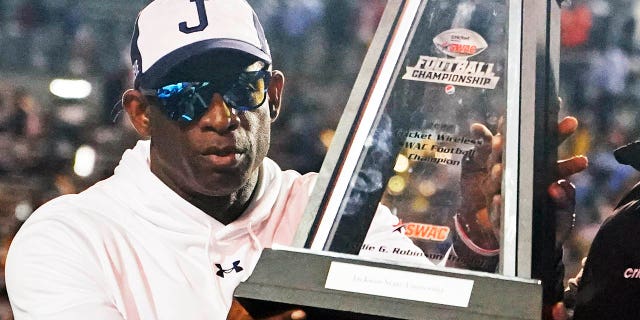 Jackson State head coach Deion Sanders hoists the winner's trophy following the Southwestern Athletic Conference championship game against Southern University, Saturday, Dec. 3, 2022. Jackson State won 43-24.