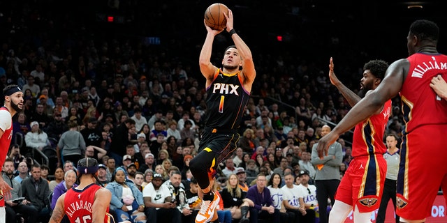 Suns guard Devin Booker shoots as New Orleans Pelicans guard Jose Alvarado falls, Saturday, Dec. 17, 2022, in Phoenix.