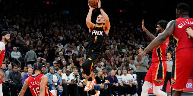 Phoenix Suns guard Devin Booker (1) shoots as New Orleans Pelicans guard Jose Alvarado (15) falls during the second half of an NBA basketball game, Saturday, Dec. 17, 2022, in Phoenix. 