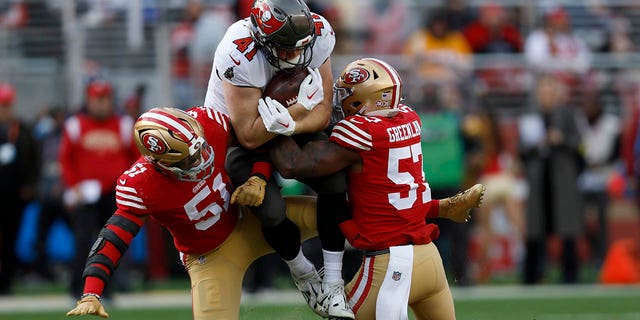 Tampa Bay Buccaneers tight end Ko Kieft, middle, is tackled by San Francisco 49ers linebacker Azeez Al-Shaair (51) and linebacker Dre Greenlaw (57) during the first half of an NFL football game in Santa Clara, Calif., Sunday, Dec. 11, 2022.