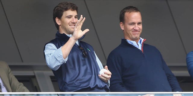 Eli Manning, of the New York Giants, and Peyton Manning, of the Denver Broncos, appear at the game between the New York Yankees and the Tampa Bay Rays on May 4, 2014 in the Bronx borough of New York City.