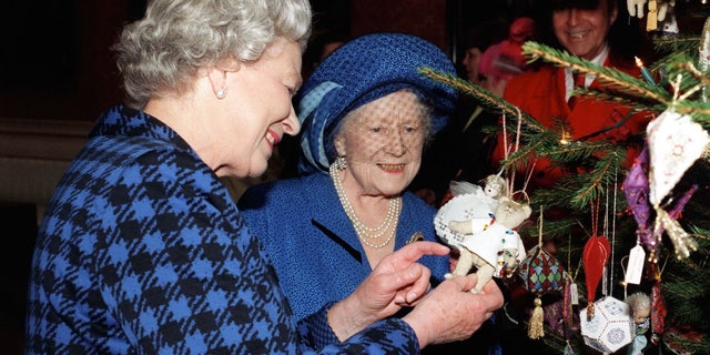 Queen Elizabeth II and Queen Elizabeth, The Queen Mother admire Christmas decorations on the Christmas tree in the Picture Gallery at Buckingham Palace on Dec. 15, 1998.