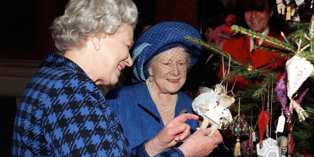 Queen Elizabeth II and Queen Elizabeth, The Queen Mother admire Christmas decorations on the Christmas tree in the Picture Gallery at Buckingham Palace on Dec. 15, 1998.