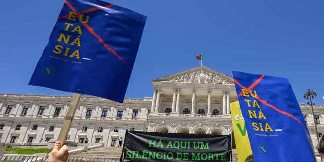 Demonstrators hold signs outside the Portuguese Parliament during a "silent demonstration" promoted by the Federation for Life on the day the Portuguese Parliament debates the bills aimed at legalizing euthanasia, on June 9, 2022, in Lisbon, Portugal. After three votes, Portugal's parliament voted in favor of allowing euthanasia in the country.