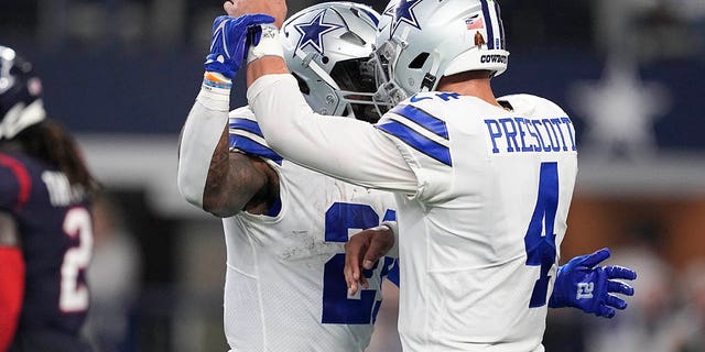 Dallas Cowboys running back Ezekiel Elliott (21) celebrates with quarterback Dak Prescott (4) after scoring a touchdown during the second half of an NFL football game against the Houston Texans, Sunday, Dec. 11, 2022, in Arlington, Texas.