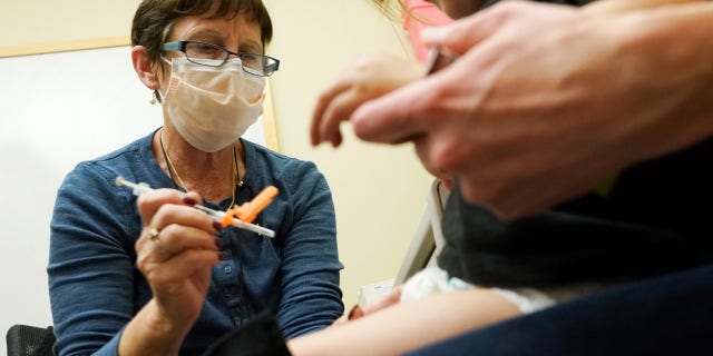 Deborah Sampson, left, a nurse at a University of Washington Medical Center clinic in Seattle, gives a Pfizer COVID-19 vaccine shot to a 20-month-old child, June 21, 2022, in Seattle.