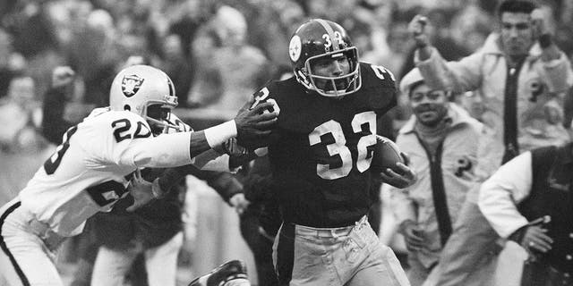 Franco Harris (32) de los Pittsburgh Steelers evade una entrada de Jimmy Warren de los Oakland Raiders mientras avanza 42 yardas para un touchdown después de atrapar un pase desviado durante un juego de playoffs de la División AFC en Pittsburgh el 23 de diciembre de 1972.