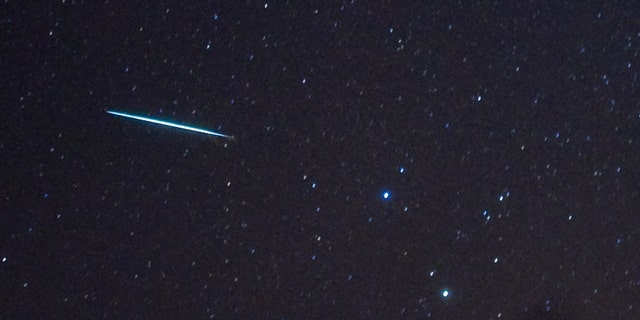 Un météore (L) de la pluie de météores des Géminides pénètre dans l'atmosphère terrestre après les étoiles Castor et Pollux (deux étoiles brillantes, R) le 12 décembre 2009 au-dessus de Southwold, New York.