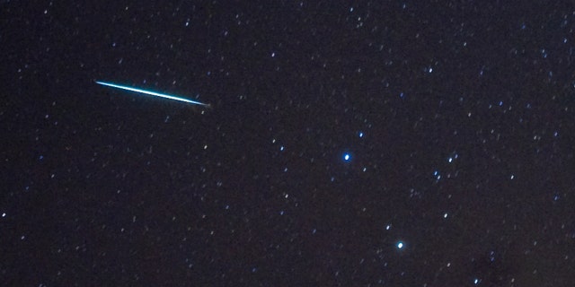 Meteor (L) z meteorického roje Geminid vstoupil do zemské atmosféry kolem hvězd Castor a Pollux (dvě jasné hvězdy, R) 12. prosince 2009 nad Southwoldem v New Yorku.