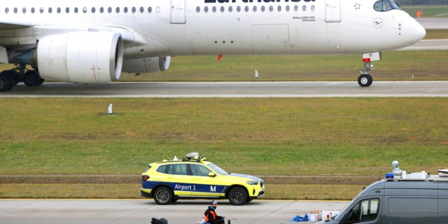 The last of four climate activists sits with his hand glued to the feeder road of a runway at Franz-Josef-Strauss Airport in Munich, Germany, Thursday, Dec. 8, 2022. 