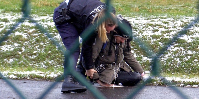 A Federal Police officer tries to remove a 'Last Generation' activist from a street at the BER Airport in Berlin, Germany, Thursday, Dec. 8, 2022. 