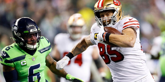 George Kittle #85 of the San Francisco 49ers carries the ball for a touchdown against the Seattle Seahawks during the first quarter of the game at Lumen Field on December 15, 2022 in Seattle, Washington.