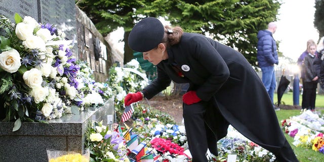 Carisa Harris-Adamson, from San Francisco, places a US flag in a wreath placed in memory of her uncle John Cummock, who was on the 1988 Pan Am flight 103 as it was bombed over Lockerbie, during a service to mark the 30th anniversary of the Lockerbie Air Disaster, at the Memorial Garden, Dryfesdale Cemetery, Lockerbie, southwestern Scotland, on December 21, 2018. 