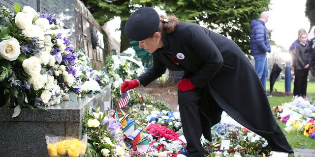 Carisa Harris-Adamson, from San Francisco, places a US flag in a wreath placed in memory of her uncle John Cummock, who was on the 1988 Pan Am flight 103 as it was bombed over Lockerbie, during a service to mark the 30th anniversary of the Lockerbie Air Disaster, at the Memorial Garden, Dryfesdale Cemetery, Lockerbie, southwestern Scotland, on December 21, 2018.