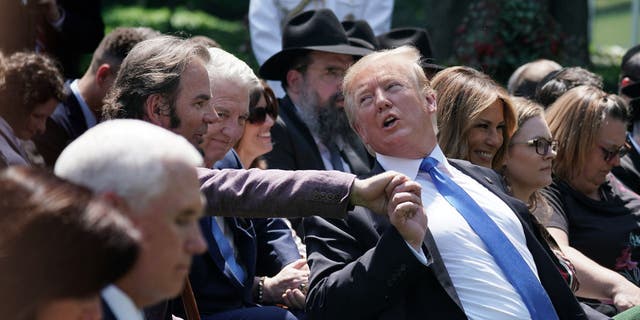 President Donald Trump grabs the hand of Jonathan Cain during a National Day of Prayer service in the Rose Garden at the White House, May 2, 2019.
