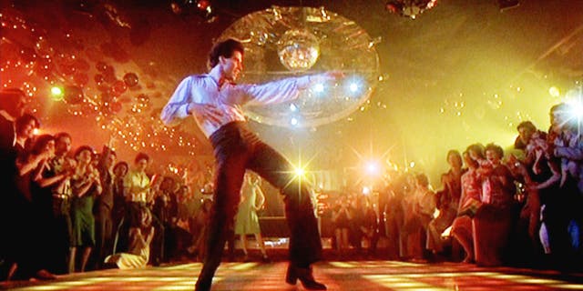 The movie "Saturday Night Fever," directed by John Badham. Seen here, John Travolta as Tony Manero on the dance floor of 2001 Odyssey discotheque. Screen capture, Paramount Pictures.