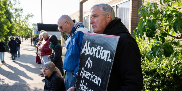 A pro-life demonstrator stands with his sign in front of EMW Women's Surgical Center, an abortion clinic, on May 8, 2021, in Louisville, Kentucky.