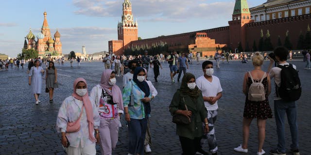 Tourists wearing face masks to protect against the coronavirus walk along Red Square on July 5, 2021, in Moscow.