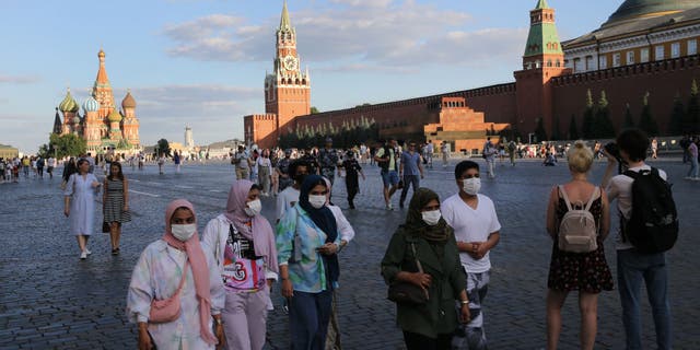 Tourists wearing face masks to protect against the coronavirus walk along Red Square on July 5, 2021, in Moscow.