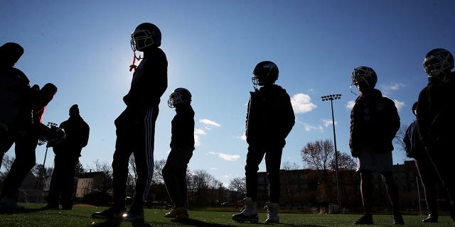 Players line up during practice for the Dorchester Eagles Pop Warner football team in the Dorchester neighborhood of Boston, Massachusetts, November 27, 2021.
