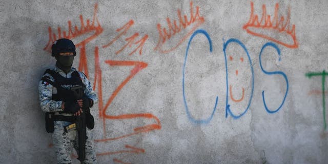 A Mexican soldier stands guard next to some graffitis of the drug trafficker Mayo Zambada and the criminal group "Cartel de Sinaloa," in Palmas Altas village, Jerez de Garcia Salinas municipality, Zacatecas state, Mexico, on March 14, 2022.