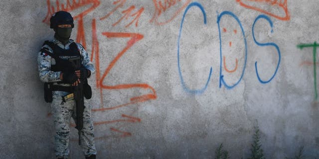 A Mexican soldier stands guard next to some graffitis of the drug trafficker Mayo Zambada and the criminal group "Cartel de Sinaloa," in Palmas Altas village, Jerez de Garcia Salinas municipality, Zacatecas state, Mexico, on March 14, 2022.