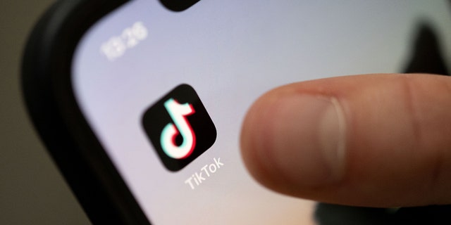 A person taps on the TikTok app on a smartphone.