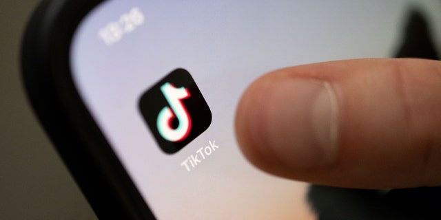 A teenager taps on the TikTok app on a smartphone. 