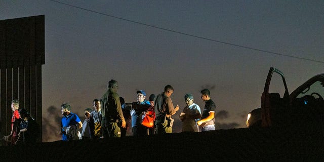 Border Patrol agents take people into custody next to the U.S.-Mexico border fence where the last of the Colorado River flows into Mexico on September 27, 2022 near Yuma, Arizona.
