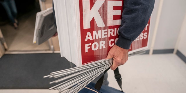 A supporter carries lawn signs for Republican Congressional candidate Joe Kent at a campaign event on October 5, 2022 in Morton, Washington. Kent, who has the support of former President Donald Trump and in the primary defeated moderate incumbent Jaime Herrera Beutler, who voted for Trump's impeachment, faces Democratic nominee Marie Gluesenkamp Perez in November for the state's 3rd Congressional District seat. 