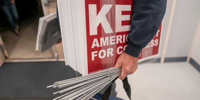 A supporter carries lawn signs for Republican Congressional candidate Joe Kent at a campaign event on October 5, 2022 in Morton, Washington.  Kent, who has the support of former President Donald Trump and in the primary defeated moderate incumbent Jaime Herrera Beutler, who voted for Trump's impeachment, faces Democratic nominee Marie Gluesenkamp Perez in November for the state's 3rd Congressional District seat. 