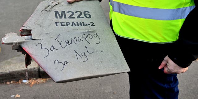 Ein Polizeiexperte hält ein Fragment einer Drohne mit einer handschriftlichen Inschrift darauf "nach Belgorod.  Schmerle" Nach einem Drohnenangriff in Kiew am 17. Oktober 2022 inmitten der russischen Invasion in der Ukraine. 