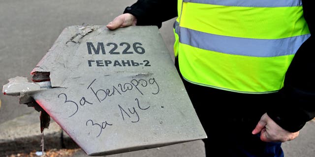 A police expert holds a fragment of a drone with a handwritten inscription "For Belgorod. For Luch" after a drone strike in Kyiv on October 17, 2022 amid the Russian invasion of Ukraine.