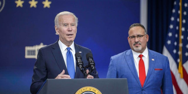 President Joe Biden speaks on his student loan handout as Education Secretary Miguel Cardona listens at the White House campus on Oct. 17, 2022.