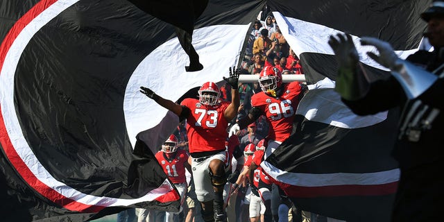 Georgia Bulldogs offensive lineman Xavier Truss (73) and defensive lineman Zion Logue (96) lead the team onto the field before a game against the Georgia Tech Yellow Jackets Nov. 26, 2022, at Sanford Stadium in Athens, Ga. 
