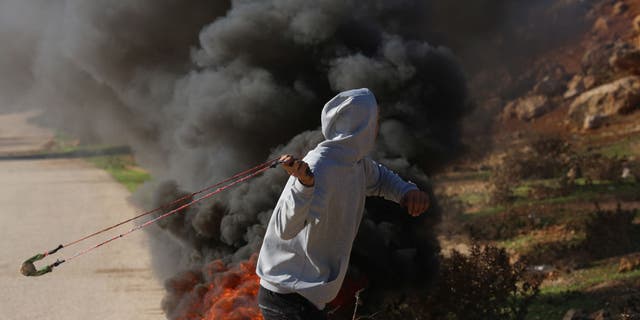 A Palestinian man uses a catapult against Israeli troops during a protest against new construction at Jewish settlements in the West Bank. 