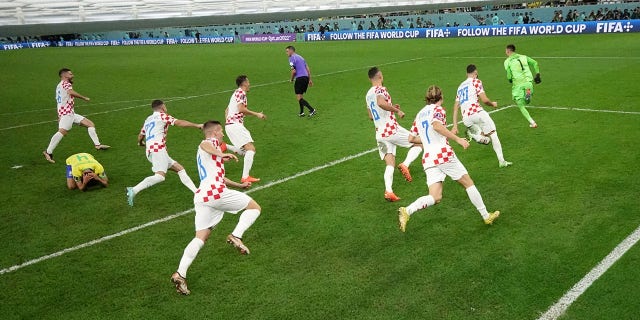 Croatia's Dominik Livakovic and teammates celebrate qualifying for the semifinals as Brazil's Marquinhos looks dejected after being eliminated from the World Cup during the FIFA World Cup Qatar 2022 quarterfinal match between Croatia and Brazil at Education City Stadium on Dec. 9, 2022 in Al Rayyan, Qatar. 