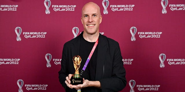 Grant Wahl stands with a World Cup replica trophy in recognition of his achievement covering eight or more FIFA World Cups during a ceremony at the Main Media Centre Nov. 29, 2022, in Doha, Qatar. 