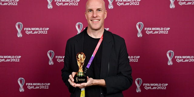 Grant Wahl stands with a World Cup replica trophy in recognition of his achievement covering eight or more FIFA World Cups during a ceremony at the Main Media Centre Nov. 29, 2022, in Doha, Qatar. 